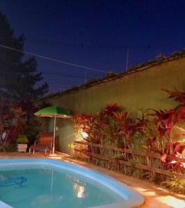 una piscina frente a una pared con sombrilla en Casa Sobrado com piscina Santa Felicidade 6 pessoa en Curitiba