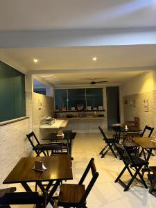 a restaurant with wooden tables and chairs and a kitchen at Pousada Portico de Buzios in Armacao dos Buzios