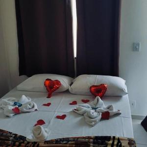 Una cama con corazones rojos y toallas. en Pousada Portico de Buzios, en Armacao dos Buzios