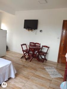 Habitación con mesa, sillas y TV de pantalla plana. en Pousada Cantinho do João Gabriel, en São Gabriel