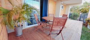 Appartement cosy في فورت-دو-فرانس: طاولة وكراسي خشبية على شرفة مع نبات الفخار