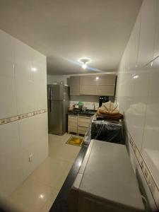 uma cozinha com paredes brancas e uma cozinha com um frigorífico em Casa Paraíso Costeiro em Iguaba Grande