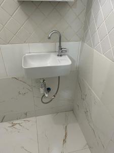 a white sink in a white tiled bathroom at Quarto privativo em casa domiciliar in Campo Grande