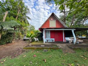 a red house with a bench in front of it at Las Casitas de Playa Pochote. in Pochote