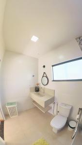 a white bathroom with a toilet and a sink at Blue House Vale do Capão in Palmeiras