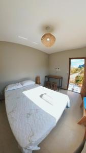 a large white bed in a bedroom with a window at Blue House Vale do Capão in Palmeiras