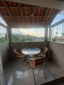 a table and chairs in a room with windows at Pousada Recanto do Canário 2 in Governador Celso Ramos