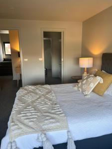 a bedroom with a bed with white sheets and a lamp at Inner City Pad in Ballarat