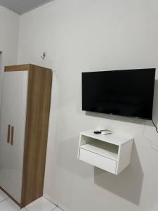 a living room with a tv and a white wall at Flat Davisis 4 - Rodoviária Faculdades e Aeroporto in Palmas