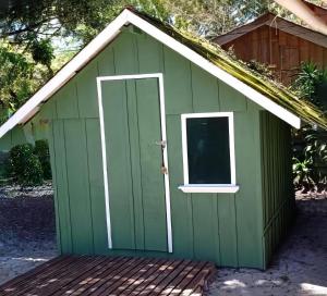 um barracão verde com uma porta e uma janela em Pousada e Camping do Clodo na Ilha do Mel