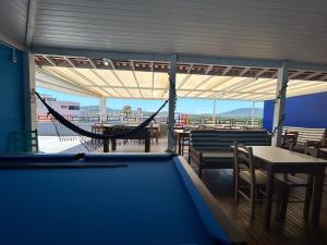 a room with a hammock and tables and chairs at Ilha azul hospedagem in Florianópolis