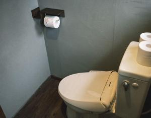 a bathroom with a toilet and a roll of toilet paper at The Greenhouse in Myoko