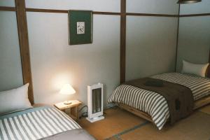 a room with two beds and a television in it at The Greenhouse in Myoko