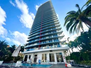 a tall building with a pool in front of it at MVR Apartments at Beachwalk Resort in Hallandale Beach