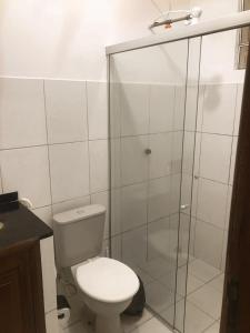 a bathroom with a toilet and a glass shower at Pousada Marajó For You in Soure