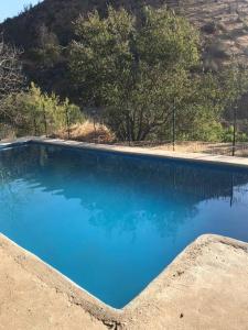 una gran piscina de agua azul con árboles en el fondo en Casa en el campo en Quebrada Alvarado, en Olmué