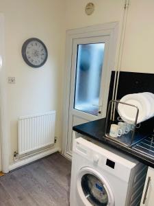 lavadora en una habitación con reloj en la pared en Baravaggio By Kasar Stays en Leicester