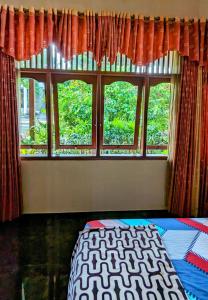 una camera da letto con tre finestre e un letto sul davanti di Sleepy Raccoon Hostel a Yogyakarta