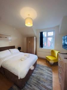 a bedroom with a large bed and a yellow chair at Baravaggio By Kasar Stays in Leicester
