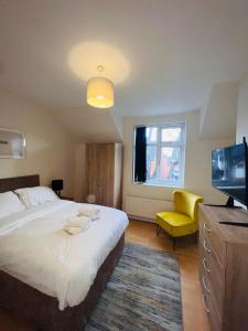 a bedroom with a large bed and a yellow chair at Baravaggio By Kasar Stays in Leicester