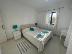 a white bedroom with a bed with towels on it at Pissouri Beach Apartments in Pissouri
