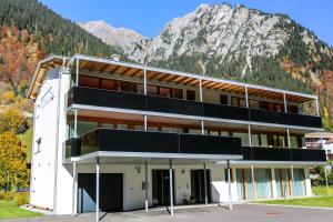 ein Gebäude mit einem Berg im Hintergrund in der Unterkunft Apart Sportiva in Klösterle am Arlberg