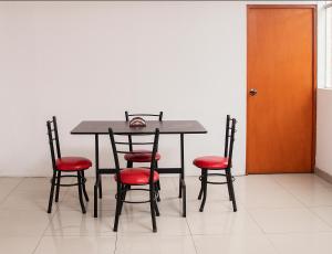 a dining room table with four chairs and a door at Lujoso Departamento ,Iluminado , 5 minutos Centro in Tacna