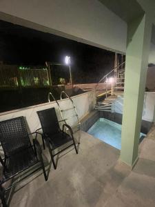 ゴヴェルナドール・セウソ・ラーモスにあるPousada Recanto do Canário 3の- パティオ(椅子2脚付)、夜間のスイミングプール
