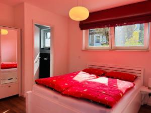 a bedroom with pink walls and a bed with red sheets at House Water Jieper near the beach in Göhren-Lebbin