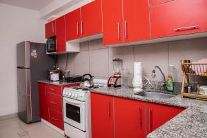 a kitchen with red cabinets and a white stove top oven at Lujoso Departamento ,Iluminado , 5 minutos Centro in Tacna