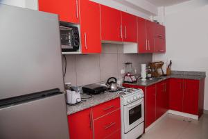 a kitchen with red cabinets and a white stove top oven at Lujoso Departamento ,Iluminado , 5 minutos Centro in Tacna