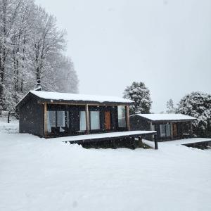 a house covered in snow in a snow covered yard at k10lodge in Curacautín