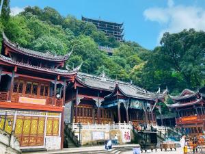 un edificio asiatico con una montagna sullo sfondo di Wuyu Hotel Chongqing Zoo & Yangjiaping The Mixc Light rail a Chongqing