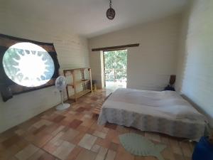 a bedroom with a large bed and a window at Casona de Barro in Imbassai