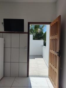 uma porta aberta com uma televisão numa parede branca em Mazz_q_casa em Ilhabela