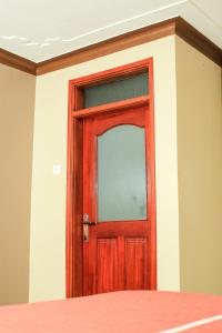 una puerta de madera con una ventana en una habitación en Triple Tee Gardens & Accomodation en Wakiso