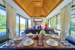 una sala da pranzo con tavolo, piatti e bicchieri di 3 Bed Luxury Bali Style Villa Close To Beach PR6 a Ban Bo Kaeo