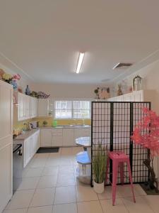 a kitchen with white cabinets and a pink stool at North Ryde Guesthouse in Sydney