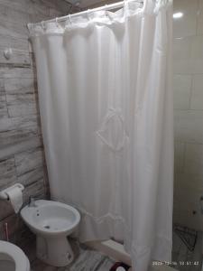 a bathroom with a white shower curtain and a toilet at Rico in Mar de Ajó +1 photo