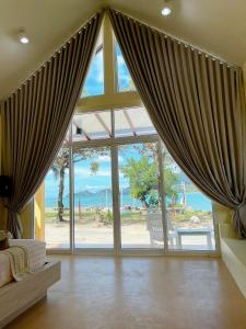 a living room with a large window with curtains at Chokdee Resort in Ko Chang