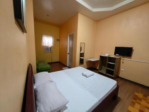 a bedroom with a large bed and a television at Lagnason's Place in Oslob