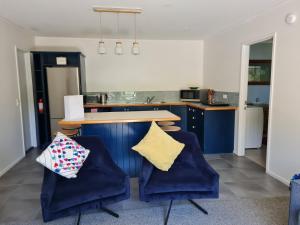 a kitchen with two blue chairs and a counter at Mākoha Place in Nelson