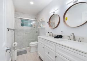een badkamer met een wastafel, een toilet en een spiegel bij Summer By The Sea in Pompano Beach