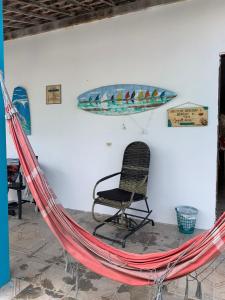 una hamaca, una silla y una tabla de surf en la pared en Estação do Mar Hostel en Porto de Galinhas