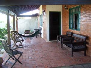 eine Terrasse mit Stühlen und einer Hängematte auf einem Haus in der Unterkunft Casa de seis suites na beira do mar in Rio das Ostras