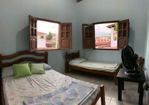 a bedroom with two beds and two windows at Estação do Mar Hostel in Porto De Galinhas