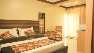 ein Schlafzimmer mit einem Bett und einem Tisch in einem Zimmer in der Unterkunft Triple Tee Gardens & Accomodation in Wakiso