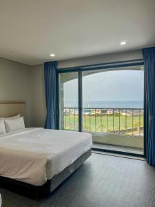 a bedroom with a large bed and a large window at Aewol Stay in Jeju Hotel&Resort in Jeju