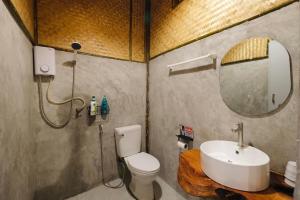 a bathroom with a sink and a toilet and a mirror at Imsuk Bo Klua in Ban Pha Khap