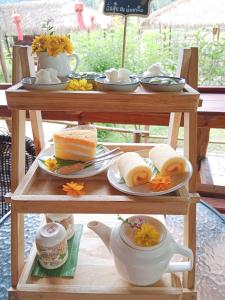 a wooden table with plates of food and a teapot at Imsuk Bo Klua in Ban Pha Khap